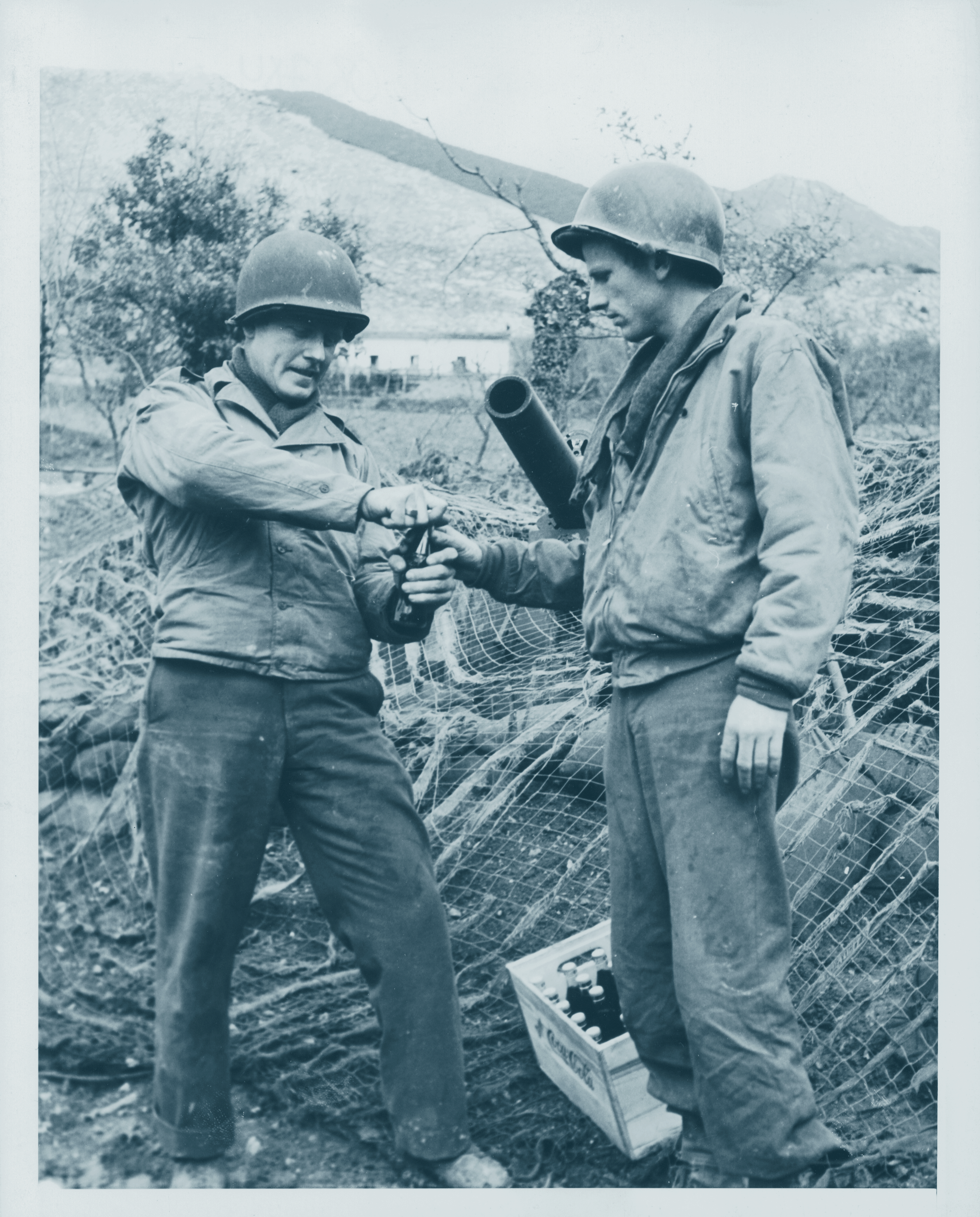 Black and white image of 2 WWII solders opening a bottle of coke